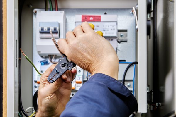 Connecting four-core, three-phase power cable to power supply in an outdoor electrical box, stripping ends of wires of insulation.